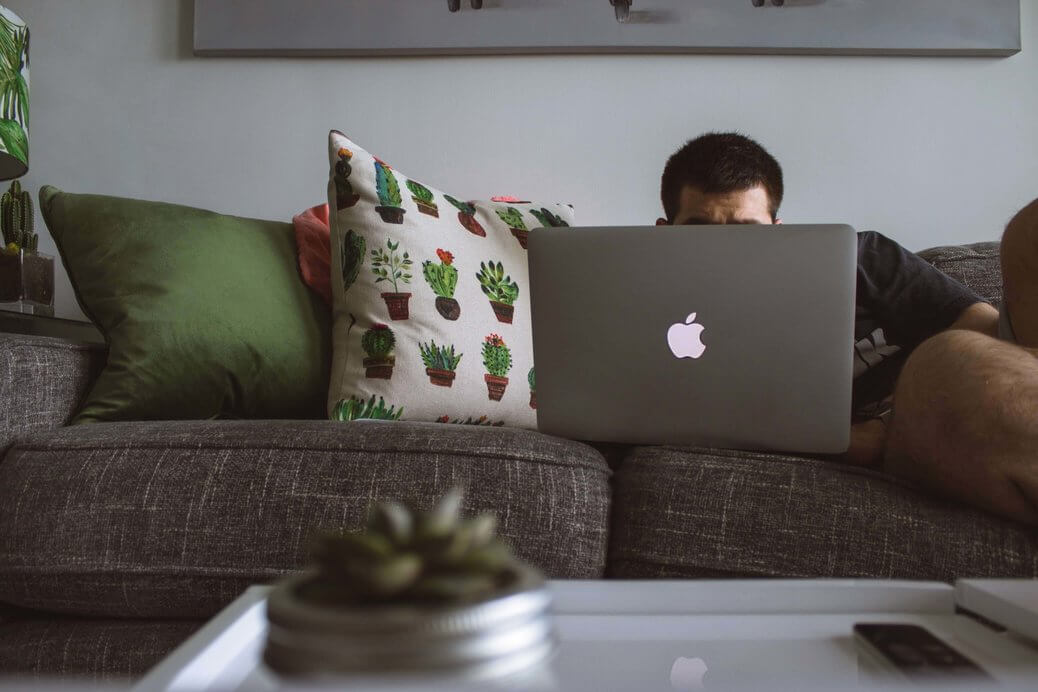 man sitting in sofa infront of computer